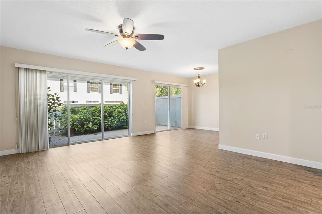 An open living and dining area features wood-look tile flooring and two sliding glass doors — 6341 TREETOP CIRCLE UNIT 6341, TEMPLE TERRACE, FL