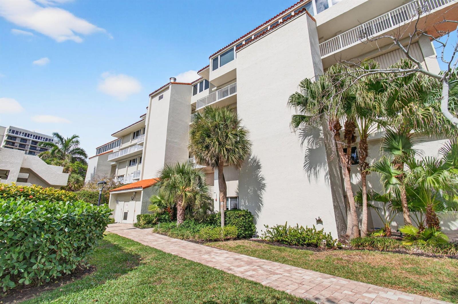 A multi-story residential building with balconies, palm trees, and a paved walkway — 3908 S Ocean Boulevard # 127, Highland Beach FL 33487, HIGHLAND BEACH, FL