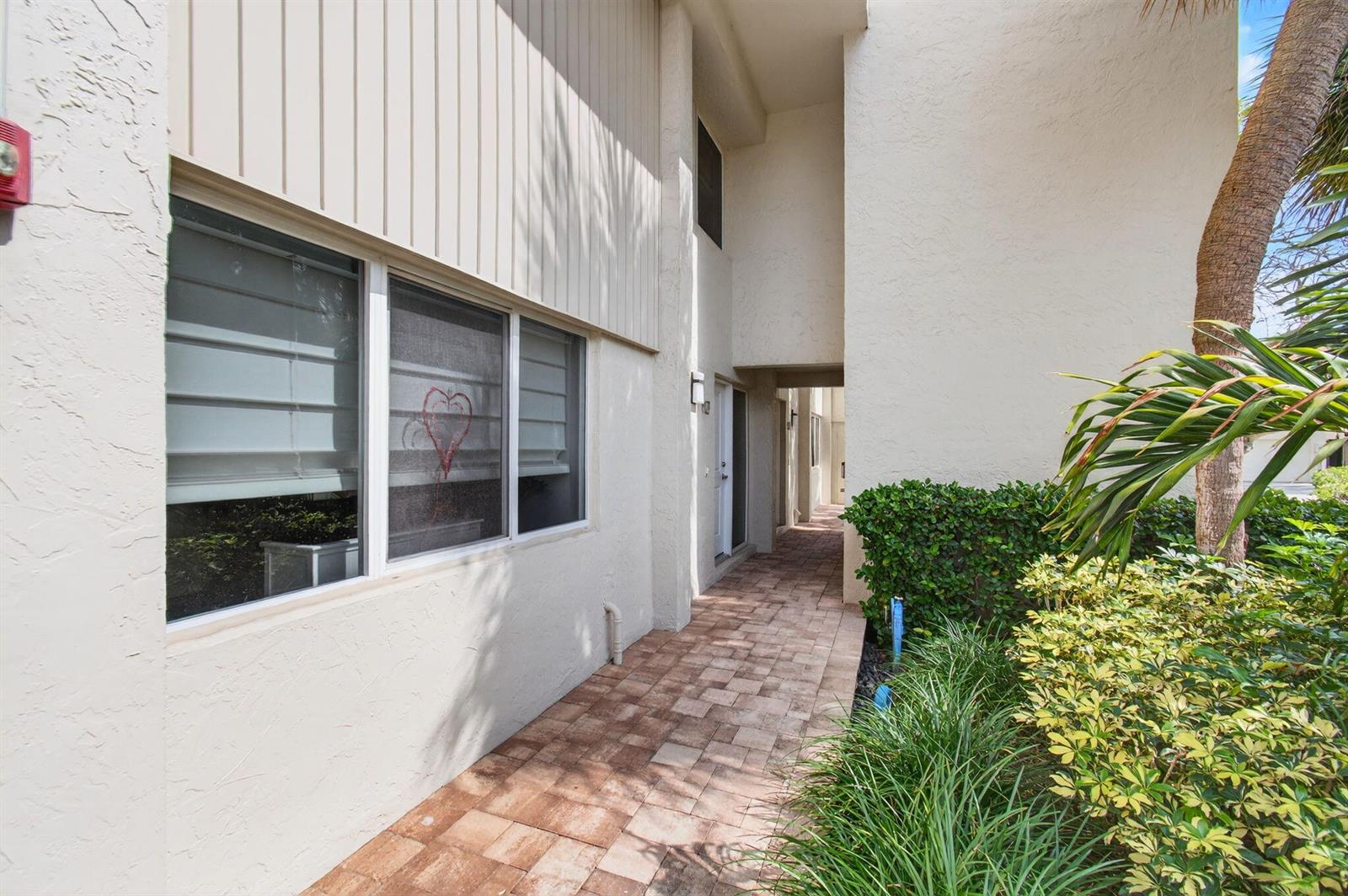A paved walkway leads to a building entrance with a window featuring a heart decal — 3908 S Ocean Boulevard # 127, Highland Beach FL 33487, HIGHLAND BEACH, FL