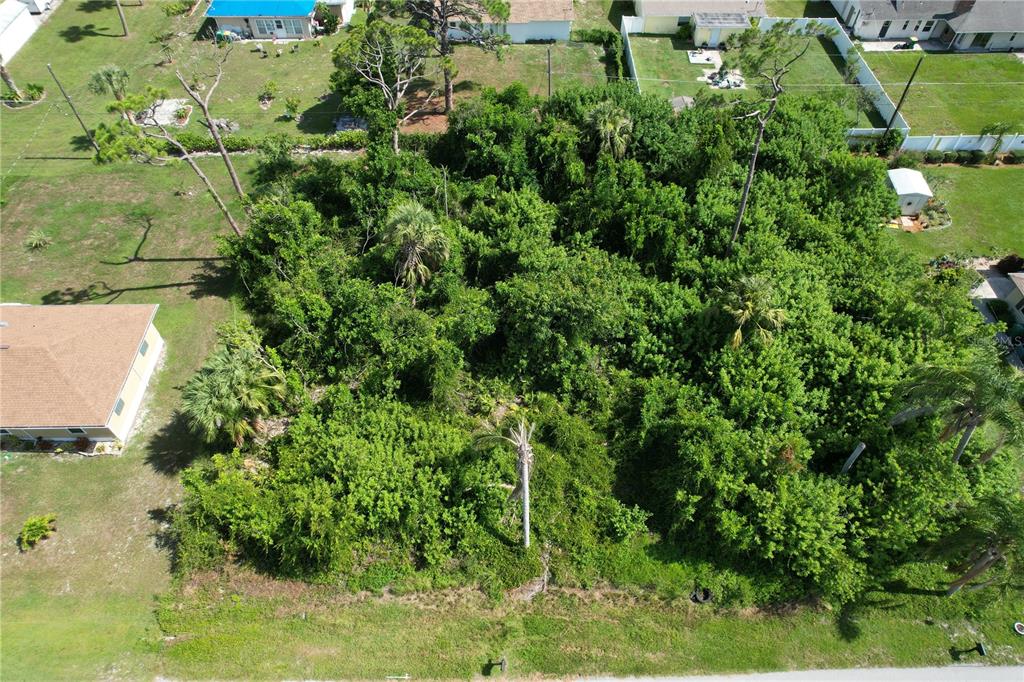 An aerial view shows a heavily wooded, undeveloped residential lot surrounded by neighboring houses — 507 MERIDAN AVENUE NW, PORT CHARLOTTE, FL
