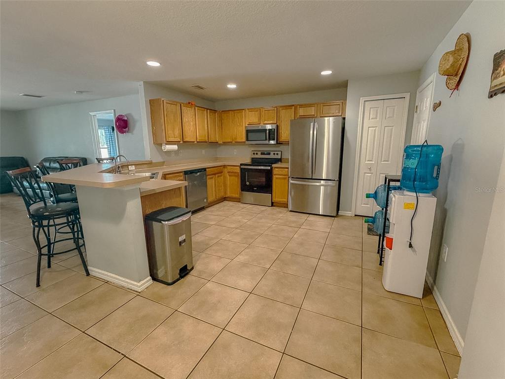 A kitchen with light wood cabinets, stainless steel appliances, and tan tile flooring — 15193 SW 46TH CIRCLE, OCALA, FL