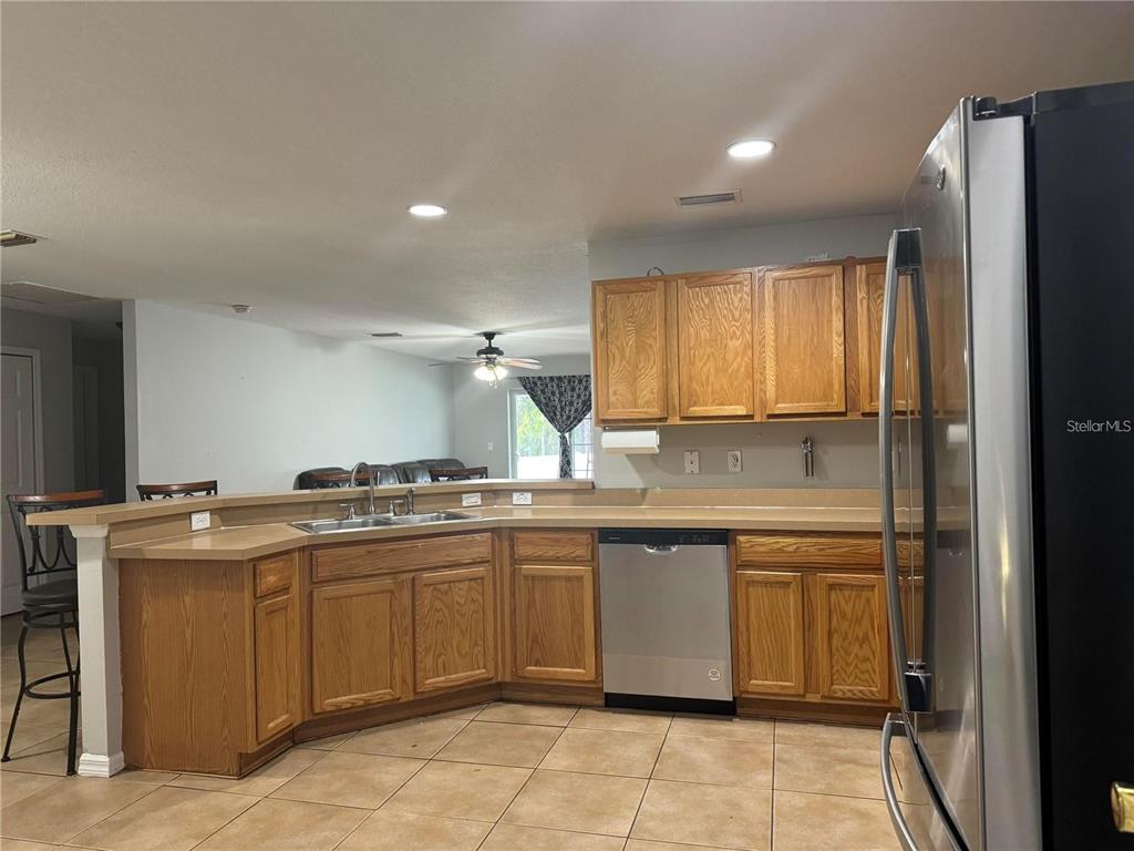 A kitchen features wood cabinets, a stainless steel dishwasher, and a breakfast bar — 15193 SW 46TH CIRCLE, OCALA, FL
