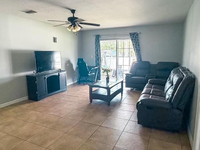 A living room features tile flooring, a ceiling fan, a television console, and leather furniture — 15193 SW 46TH CIRCLE, OCALA, FL