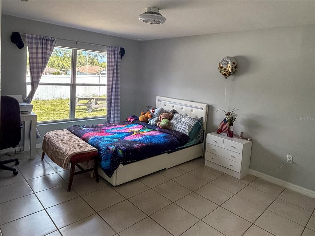 A bedroom features a bed with a colorful comforter, a white dresser, and tile flooring — 15193 SW 46TH CIRCLE, OCALA, FL