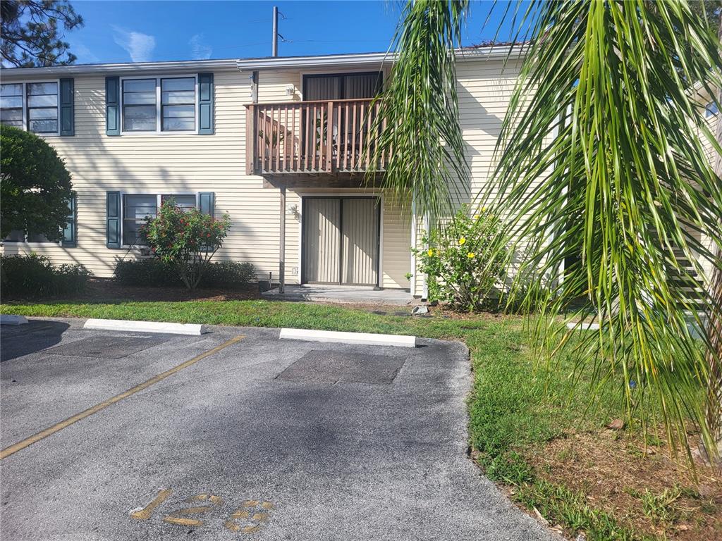 A two-story apartment building with beige siding, a wooden balcony, and a parking lot — 140 HUNTER LAKE DRIVE UNIT F, OLDSMAR, FL