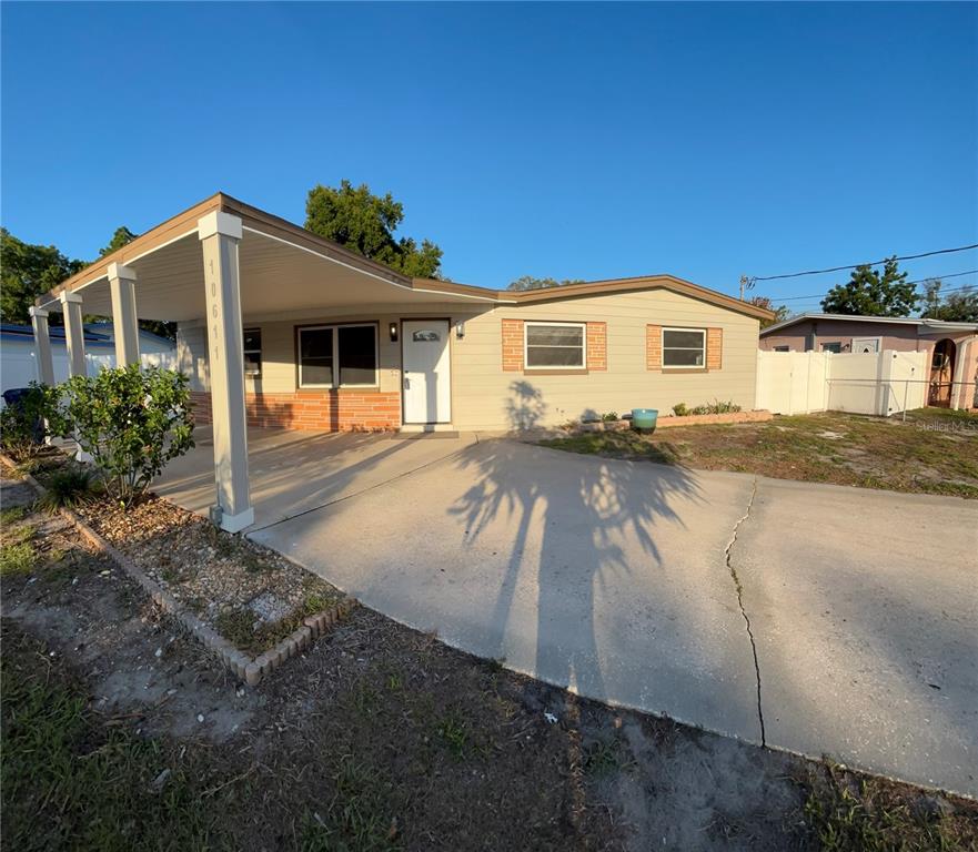 A single-story house features a carport, a concrete driveway, and light-colored horizontal siding — 10611 N ALTMAN STREET, TAMPA, FL
