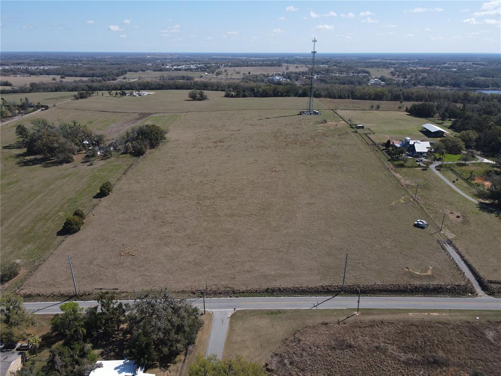 An aerial view shows a large, flat, grassy field with a tall communication tower — 10740 FORT KING ROAD, DADE CITY, FL