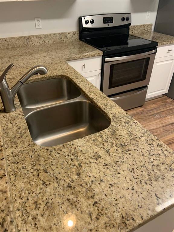 A kitchen features a stainless steel sink, granite countertops, and a stainless steel electric range — 38 LINDSAY DRIVE UNIT A, PALM COAST, FL