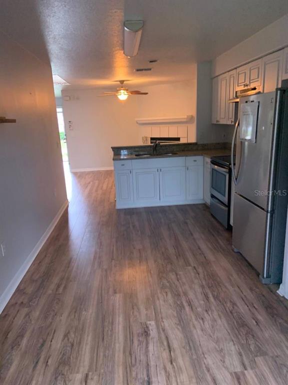 A kitchen with white cabinets and stainless steel appliances opens into a living area — 38 LINDSAY DRIVE UNIT A, PALM COAST, FL