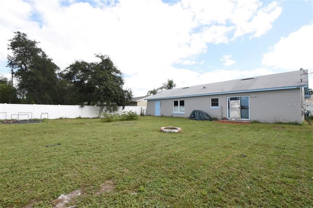 A backyard with a grassy lawn, a fire pit, and the rear exterior of a house — 2924 GIMLET DRIVE, DELTONA, FL