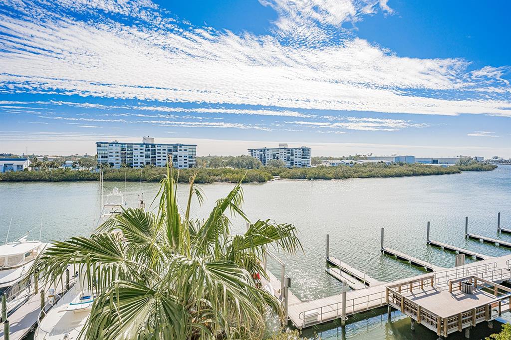 An elevated view of a marina with boats, a wooden dock, and distant apartment buildings — 399 2ND STREET UNIT 416, INDIAN ROCKS BEACH, FL