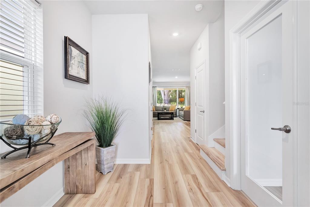 A bright entryway features light wood flooring, a console table, and a view into the living room — 5972 SACRED OAK AVENUE, MOUNT DORA, FL