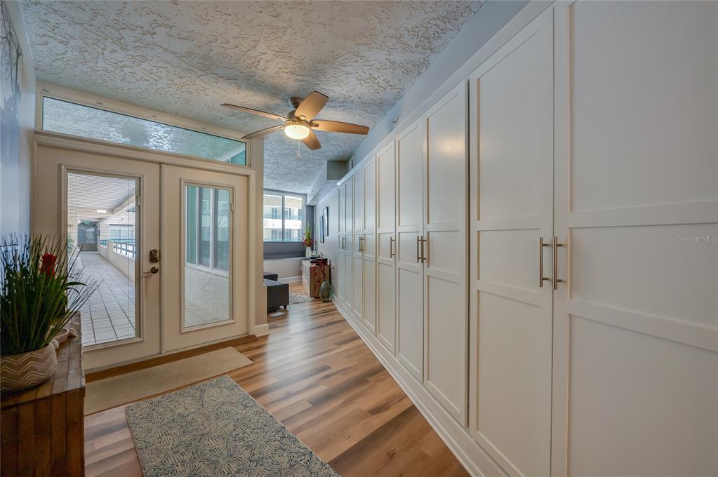 A hallway features wood-look flooring, a ceiling fan, and a wall of white storage cabinets — 4565 S ATLANTIC AVENUE UNIT 5204, PONCE INLET, FL
