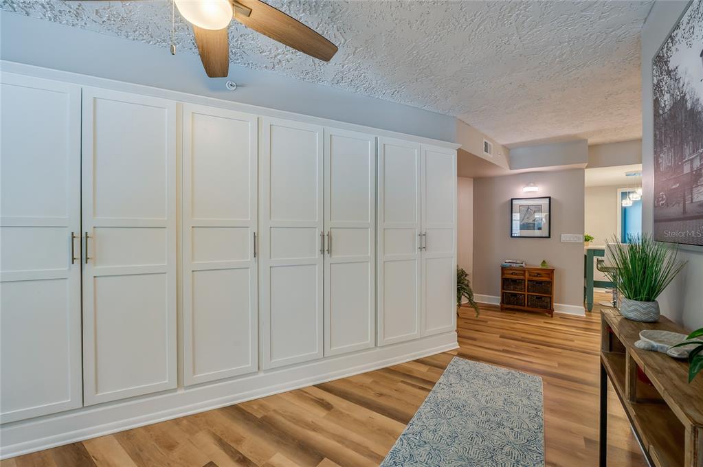 A hallway features white floor-to-ceiling cabinets, wood-look flooring, and a blue patterned runner rug — 4565 S ATLANTIC AVENUE UNIT 5204, PONCE INLET, FL