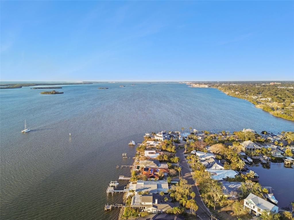 An aerial view shows waterfront houses along a coastline with a boat in the water — 1836 VENETIAN POINT DRIVE, CLEARWATER, FL