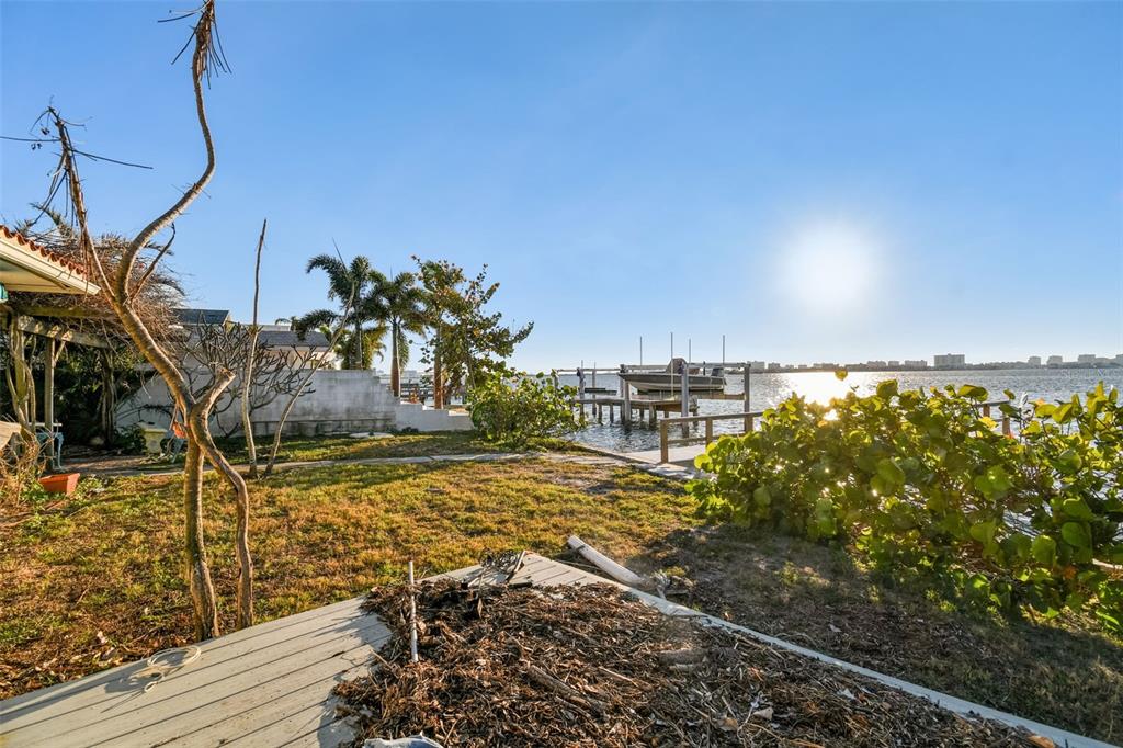 A backyard lawn leads to a private boat dock on a sunny waterfront — 1836 VENETIAN POINT DRIVE, CLEARWATER, FL