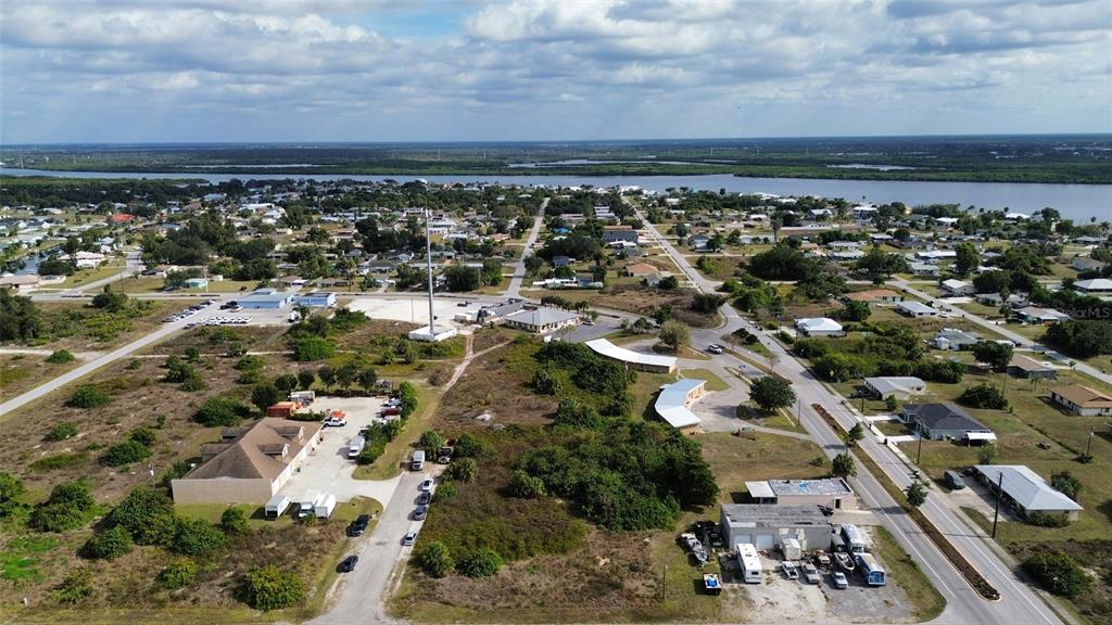 An aerial view shows a coastal town with scattered buildings, a cell tower, and vegetation — 3104 CARDIFF STREET, PUNTA GORDA, FL