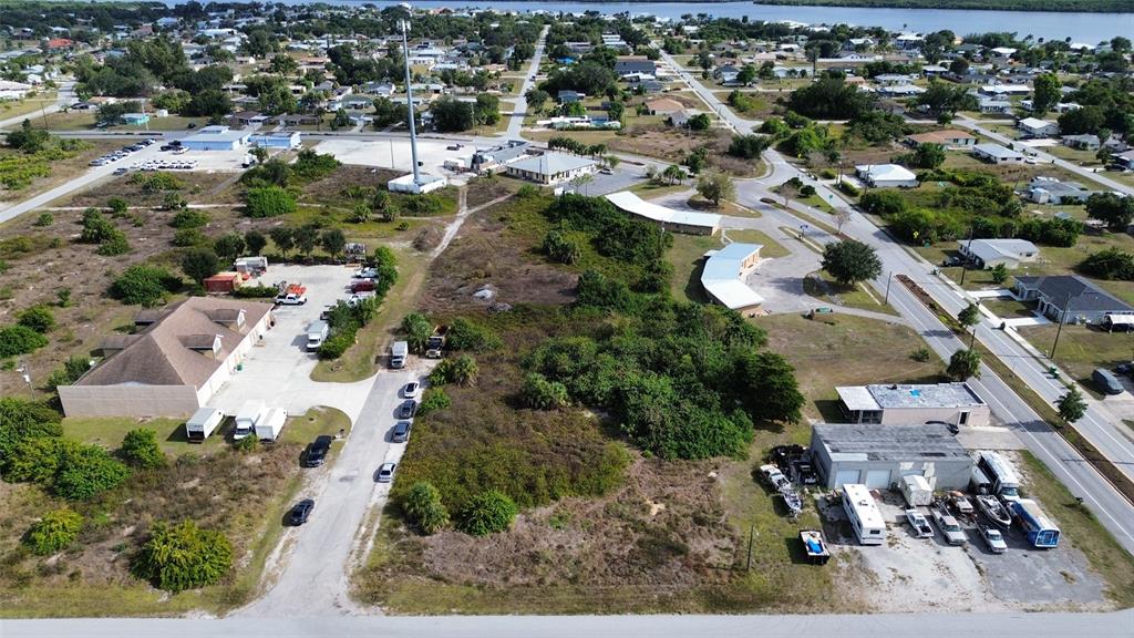 An aerial view shows a vacant lot surrounded by commercial buildings, parking areas, and roads — 3104 CARDIFF STREET, PUNTA GORDA, FL
