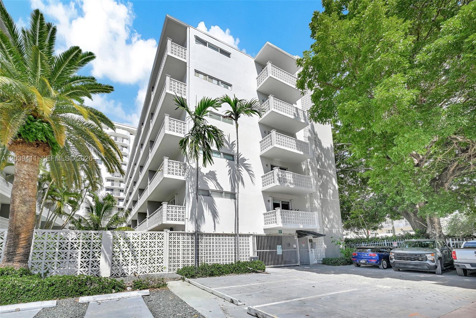 A multi-story white apartment building features balconies with decorative railings and a ground-level parking area — 1620 West Ave # 603, Miami Beach FL 33139, MIAMI BEACH, FL
