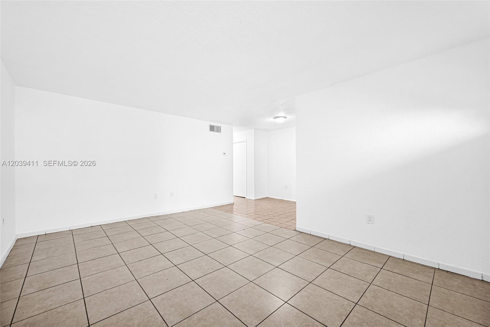 An empty room features white walls, beige tile flooring, and a doorway leading to another area — 1620 West Ave # 603, Miami Beach FL 33139, MIAMI BEACH, FL
