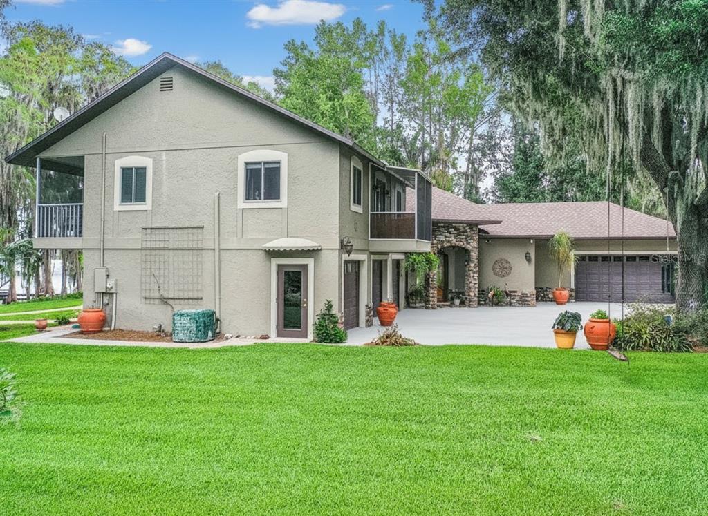 A two-story house with a stone-accented entrance, a large driveway, and a green lawn — 6850 HUNT ROAD, GROVELAND, FL