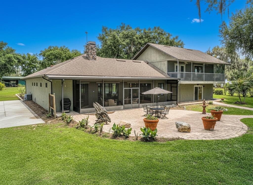 A two-story house with a screened-in patio and a paved stone terrace in the backyard — 6850 HUNT ROAD, GROVELAND, FL