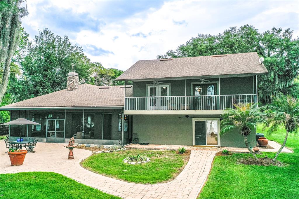 A two-story house with a screened-in patio, a balcony, and a stone paver walkway — 6850 HUNT ROAD, GROVELAND, FL