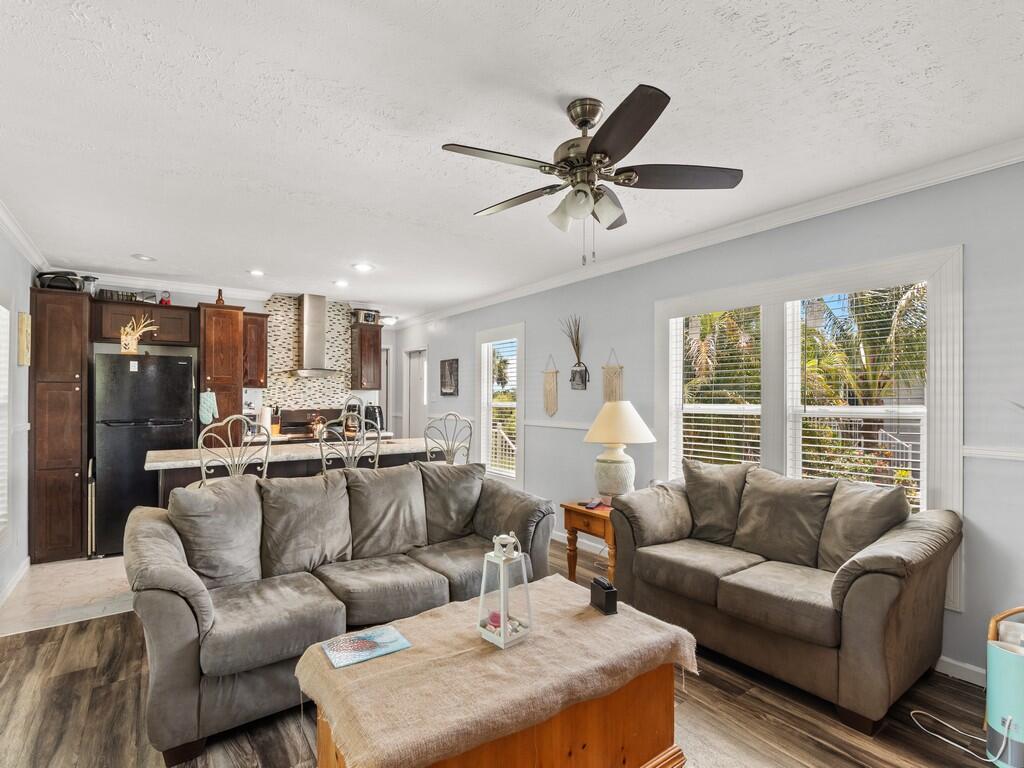 A living room with gray sofas, a wooden coffee table, and an open-concept kitchen — 309 Mockingbird Avenue, Fort Pierce FL 34982, FORT PIERCE, FL