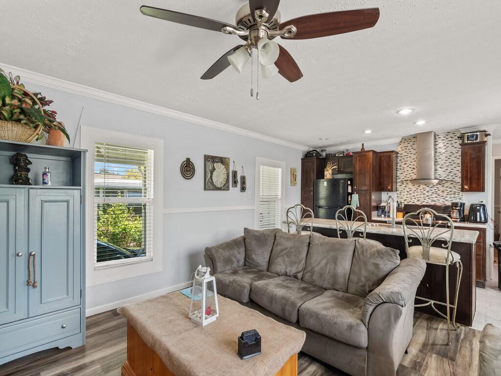 A living room with a grey sofa, wooden coffee table, and an open kitchen behind it — 309 Mockingbird Avenue, Fort Pierce FL 34982, FORT PIERCE, FL