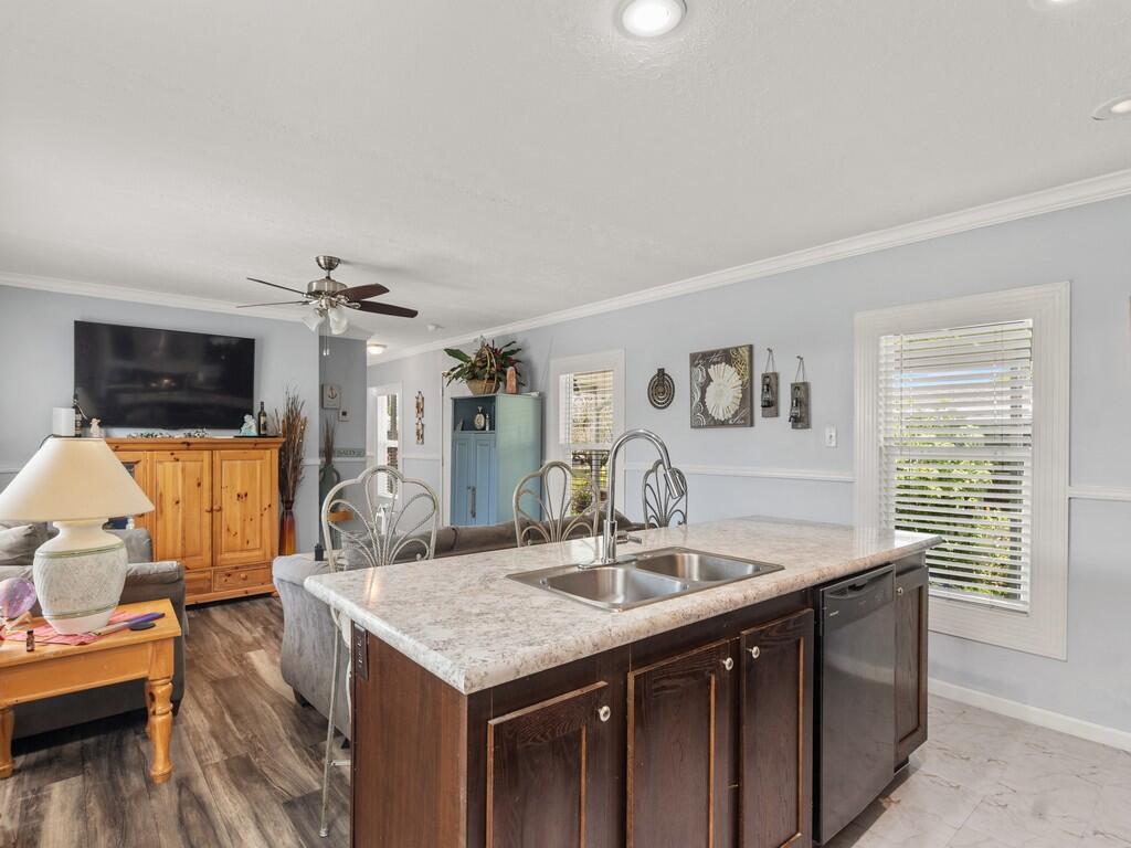 A kitchen island with a double sink and dark cabinets sits in an open-concept living area — 309 Mockingbird Avenue, Fort Pierce FL 34982, FORT PIERCE, FL