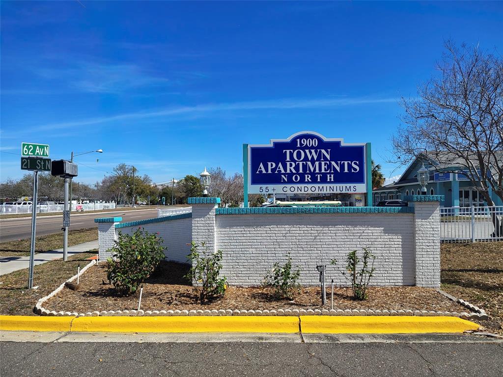 A white brick wall displays a sign for 1900 Town Apartments North 55+ Condominiums — 1950 59TH AVENUE N UNIT 119, ST PETERSBURG, FL