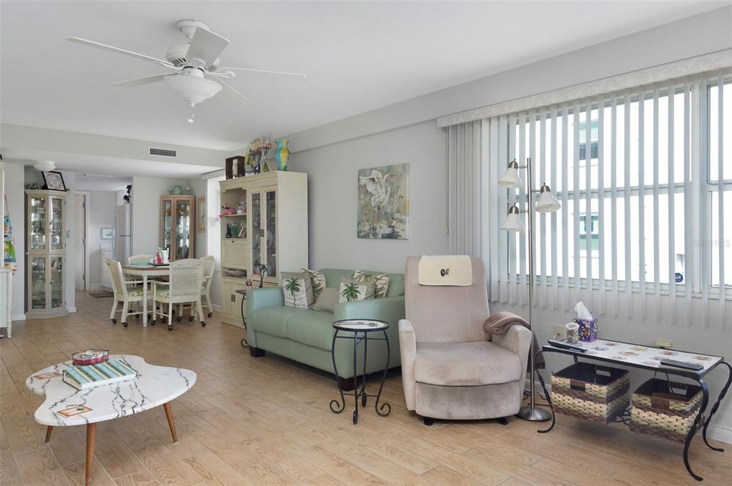 A living room features light-colored tile flooring, a green sofa, a recliner, and a dining area — 1950 59TH AVENUE N UNIT 119, ST PETERSBURG, FL