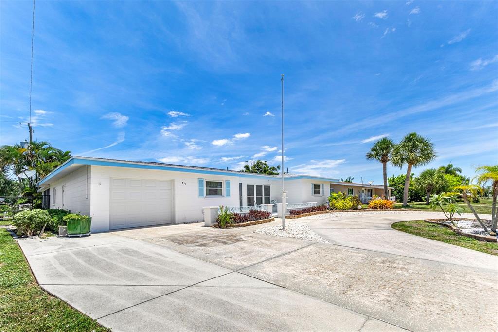 A single-story white house with a garage and a large concrete driveway under blue skies — 531 SHERIDAN DRIVE, VENICE, FL