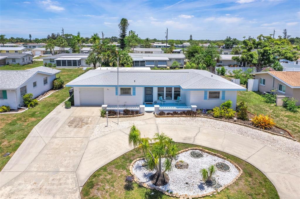 An exterior view of a white, single-story house with a circular concrete driveway and landscaping — 531 SHERIDAN DRIVE, VENICE, FL