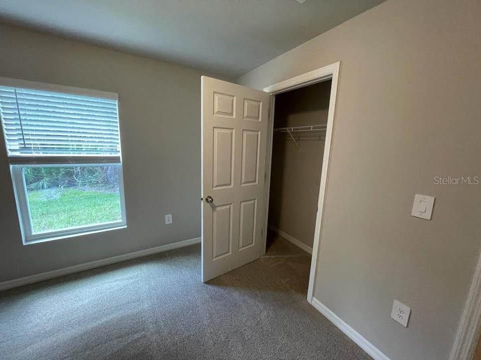 A bedroom with gray walls, carpeted flooring, a window with blinds, and an open closet — 456 MACARTHUR DRIVE, PORT CHARLOTTE, FL