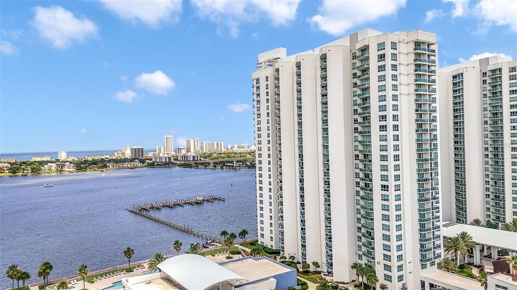 An aerial view shows a tall residential building overlooking a large body of water — 241 RIVERSIDE DRIVE UNIT 1806, DAYTONA BEACH, FL