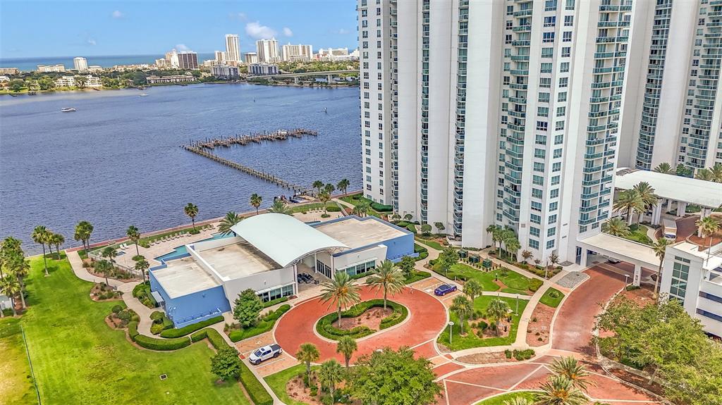An aerial view shows a tall residential building, a waterfront clubhouse, and a circular driveway — 241 RIVERSIDE DRIVE UNIT 1806, DAYTONA BEACH, FL