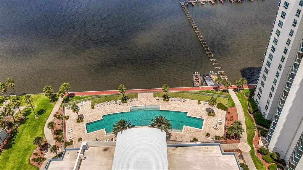 An aerial view of a waterfront swimming pool area with a pier and tall building — 241 RIVERSIDE DRIVE UNIT 1806, DAYTONA BEACH, FL