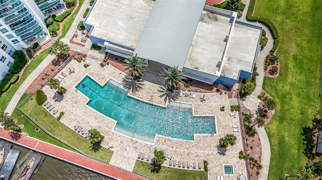 An aerial view shows a swimming pool with a stone deck next to a building — 241 RIVERSIDE DRIVE UNIT 1806, DAYTONA BEACH, FL