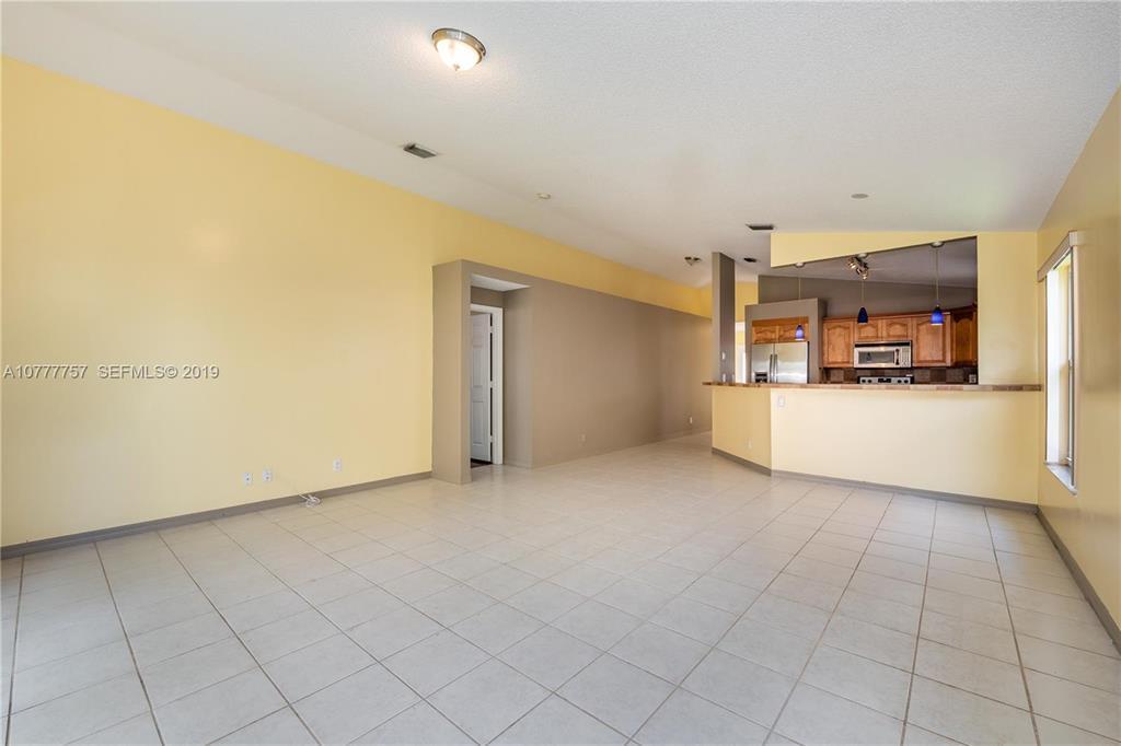 An open-concept living area features light yellow walls, white tile flooring, and a kitchen pass-through — 6222 Flores Del Mar, Margate FL 33063, MARGATE, FL