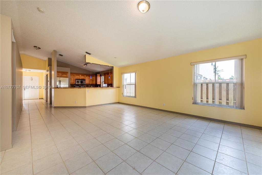 An open-concept living area features light yellow walls, tiled floors, and a kitchen pass-through — 6222 Flores Del Mar, Margate FL 33063, MARGATE, FL