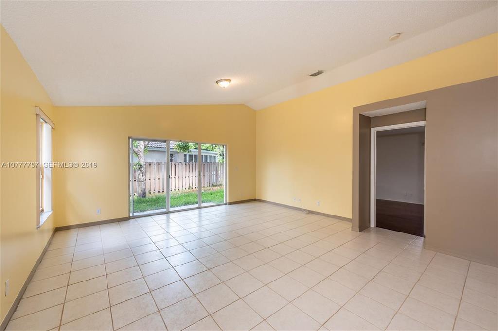 An empty room with yellow walls, tile flooring, and a sliding glass door to outside — 6222 Flores Del Mar, Margate FL 33063, MARGATE, FL