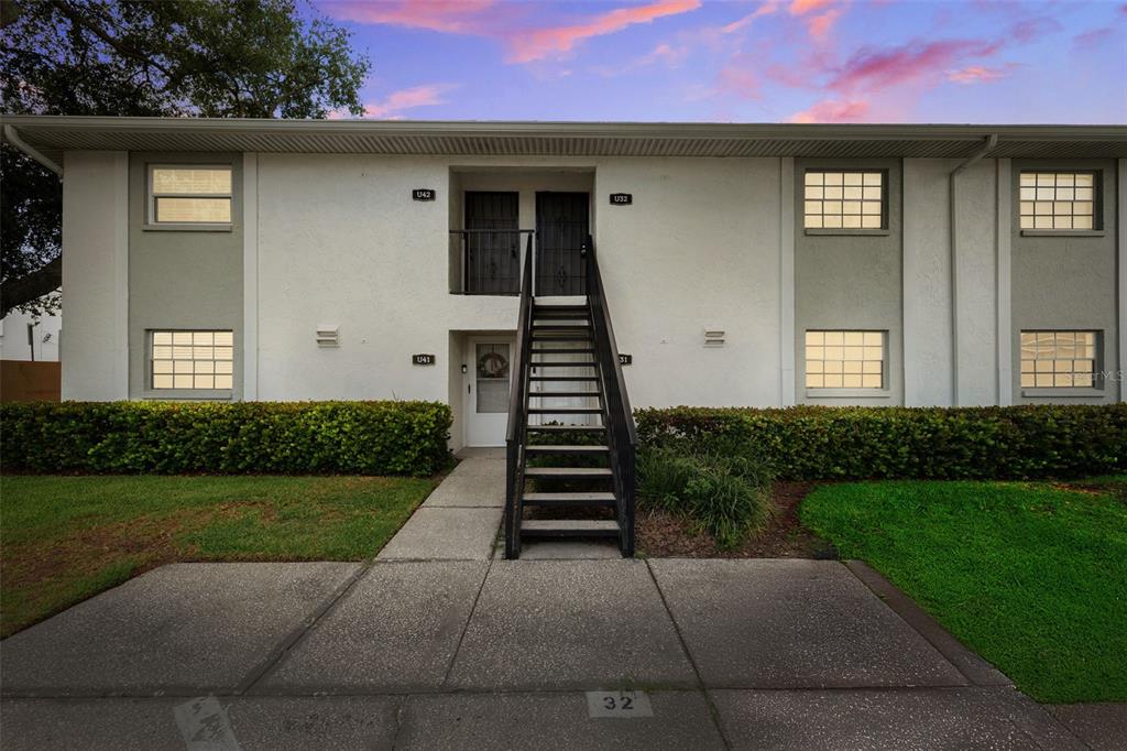A two-story apartment building exterior features a central staircase leading to upper-level unit doors — 3808 N OAK DRIVE UNIT U31, TAMPA, FL