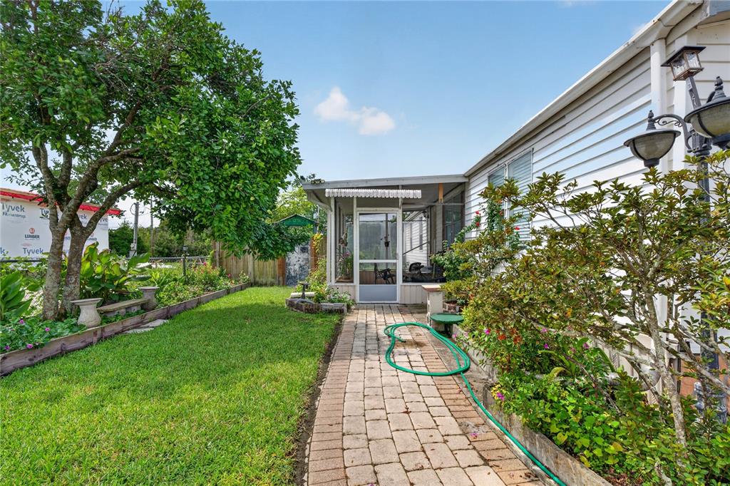 A brick walkway leads to a screened-in porch beside a house with white siding — 2558 MCINTOSH DRIVE, LAKELAND, FL