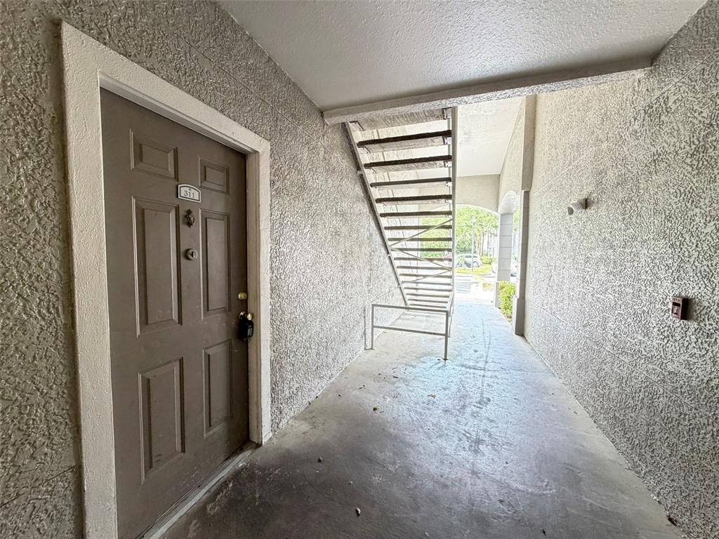 A brown apartment door labeled 311 sits next to an outdoor staircase in a hallway — 3319 S KIRKMAN ROAD UNIT 311, ORLANDO, FL