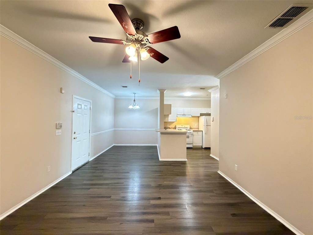 An open-concept living and dining area features wood-look flooring and a kitchen in the background — 3319 S KIRKMAN ROAD UNIT 311, ORLANDO, FL