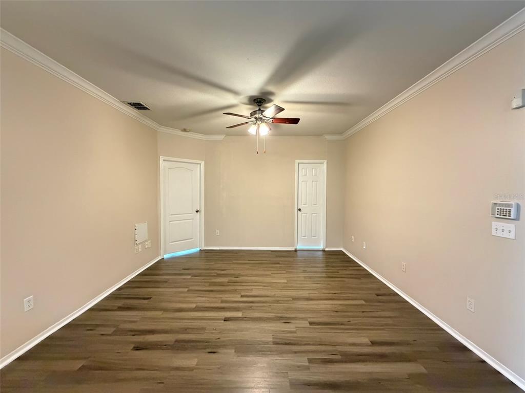 An empty room features light-colored walls, wood-look flooring, a ceiling fan, and two white doors — 3319 S KIRKMAN ROAD UNIT 311, ORLANDO, FL