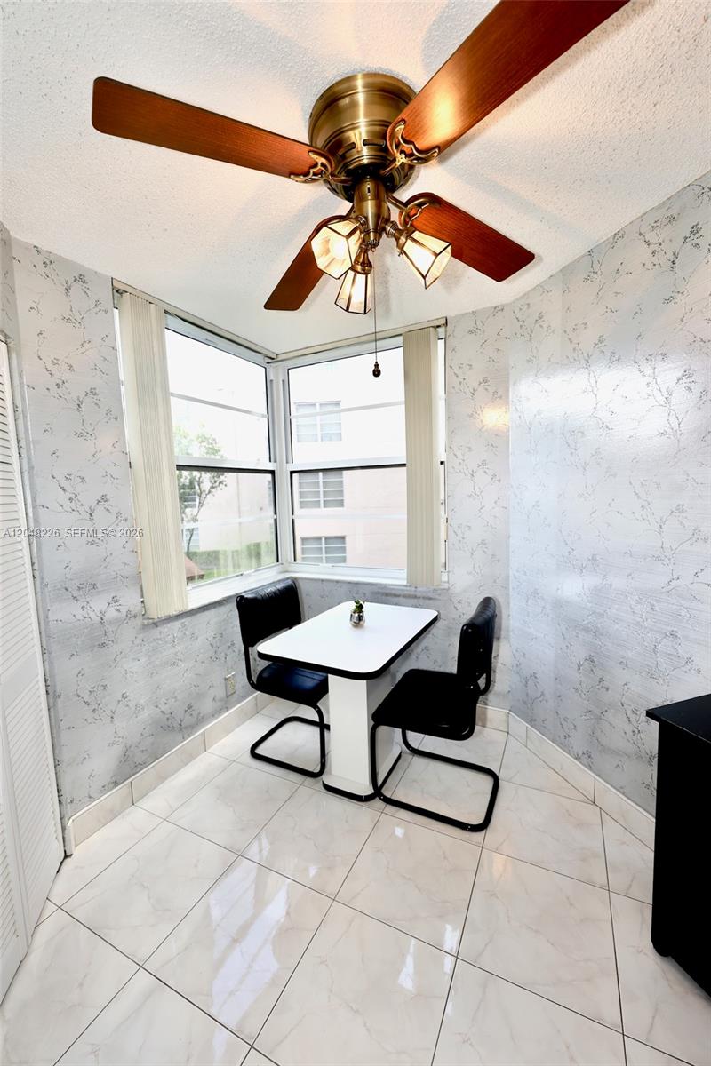 A small dining nook features a white table, two black chairs, and patterned wallpaper — 1831 Sabal Palm Dr # 208, Davie FL 33324, DAVIE, FL