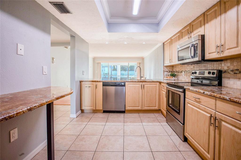A kitchen with light wood cabinets, stainless steel appliances, and granite countertops — 3300 BENEVA UNIT 214, SARASOTA, FL