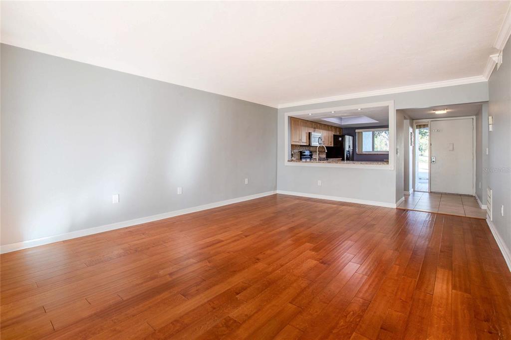 A living room with hardwood floors and a pass-through window looking into the kitchen — 3300 BENEVA UNIT 214, SARASOTA, FL
